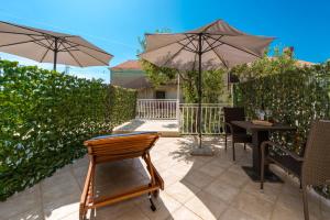 察夫塔特的住宿－Villa Adria，庭院配有遮阳伞和桌椅。