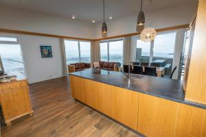 a kitchen with a bar with chairs and windows at Hrimland Cottages in Akureyri