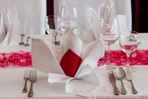 a white table with silverware and wine glasses at Hotel & Restaurant "Deutscher Kaiser" in Perleberg