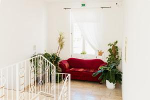 a red couch in a white room with plants at Hotel & Restaurant "Deutscher Kaiser" in Perleberg