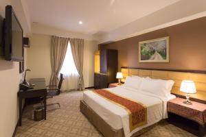 Una habitación de hotel con una cama grande y un escritorio. en Hallmark Crown Hotel, en Melaka