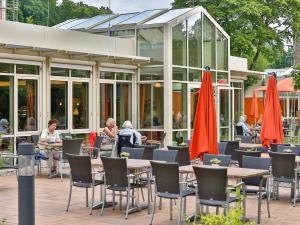 an outdoor cafe with tables and chairs and red umbrellas at GDA Hotel Göttingen in Göttingen