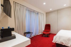 a room with a bed, chair, desk and a television at The Grove Design Hotel in Tbilisi City