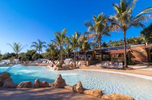 a pool at a resort with palm trees at Recanto Alvorada Eco Resort in Brotas