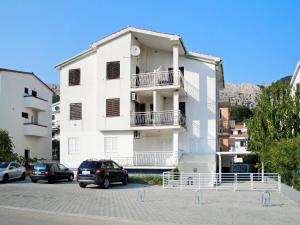 a white building with cars parked in a parking lot at Apartment Krleza in Baška