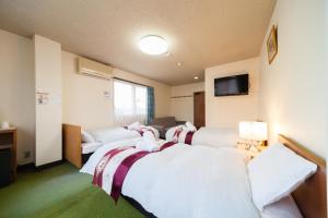 a hotel room with four beds and a couch at Petit Hotel P-Bow in Hakuba