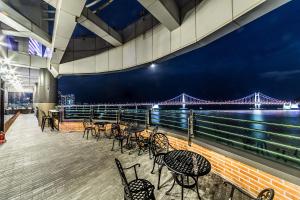 a deck with chairs and tables and a bridge at H Avenue Hotel Gwangalli branch in Busan
