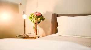 un vaso di fiori su un tavolo accanto a un letto di Collection Luxury Accommodation 7 on Murray unit 1 a Stellenbosch