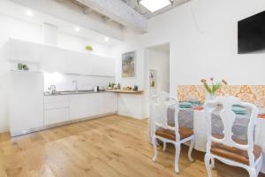 cocina con armarios blancos, mesa y sillas en GetThekey San Vitale Apartment, en Bolonia