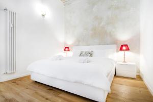 a white bedroom with a white bed and two lamps at GetThekey San Vitale Apartment in Bologna