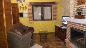 a living room with a couch and a fireplace at Alameda II con CHIMENEA Salòn y BARBACOA en patio in Curiel de Duero +7 photos