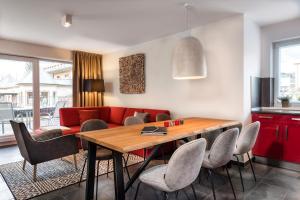 sala de estar con mesa y sofá rojo en AlpenParks Residence Bad Hofgastein - gratis Thermeneintritt en Bad Hofgastein