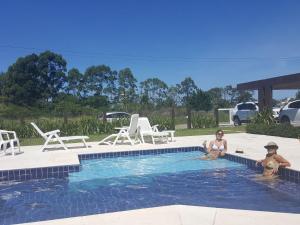 a woman and a child sitting in a swimming pool at Atlantida Park Residence in Xangri-lá