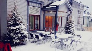 uma mesa e cadeiras na neve em frente a uma casa em Cafe-Restaurant & Hotel Saima em Savonlinna