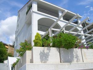 a white building with potted plants on a wall at Villa Mila in Petrovac na Moru