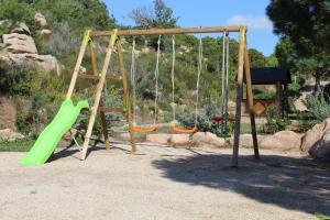 a playground with a green slide and swings at Résidence Santa Monica in Bonifacio
