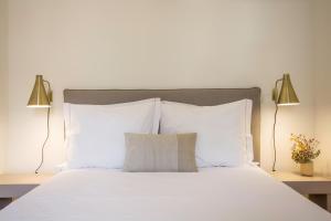 ポルトにあるOporto Sweet Home IVの白い枕とランプ2つ付きの白いベッド