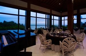a dining room with a piano and tables and chairs at Taj Bentota Resort & Spa in Bentota