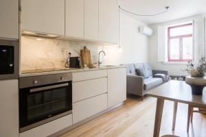 eine Küche mit weißen Schränken und ein Wohnzimmer in der Unterkunft Oporto Sweet Home IV in Porto