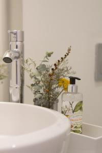 a white sink with a bottle of mouthwash next to a mirror at Oporto Sweet Home IV in Porto