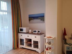 een kamer met een witte kast met een magnetron erop bij Studio 14 Strandmuschel, Residenz Seeblick in Ostseebad Sellin