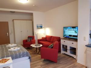 een woonkamer met een rode bank en een tv bij Studio 14 Strandmuschel, Residenz Seeblick in Ostseebad Sellin