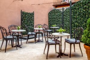 eine Terrasse mit Tischen und Stühlen vor einer Wand in der Unterkunft Hotel Della Conciliazione in Rom