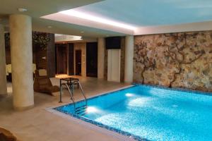 a swimming pool in a hotel with a stone wall at Premier Hotel in Krasnodar
