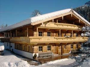 un gran edificio de madera con nieve en el techo en Appartementhaus Fuchs Christian, en Westendorf