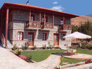 een groot stenen huis met een balkon en een parasol bij Varnous Hotel in Agios Germanos