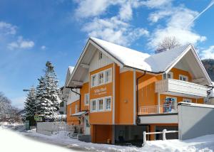 une maison orange avec de la neige sur le toit dans l'établissement Villa Florl, à Schladming