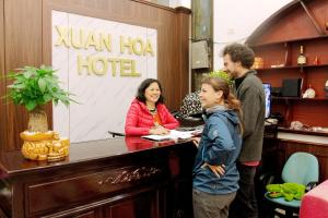een vrouw en een man die aan een hotelbalie staan bij Xuan Hoa Hotel in Ninh Binh