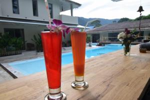 three cocktails sitting on a wooden table next to a pool at AMAYA Resort in Lamai