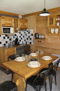 una cocina con una mesa de madera con platos y vasos. en L'Enclave, en Les Contamines-Montjoie