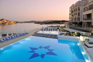 a large swimming pool next to a body of water at Super Luxury Apartment in Tigne Point, Amazing Ocean Views in Sliema