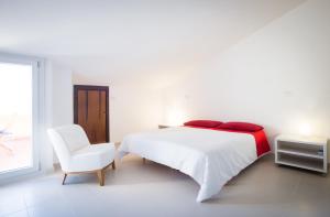 a white bedroom with a white bed and a white chair at Sa Cruxitta Apartments in Portoscuso