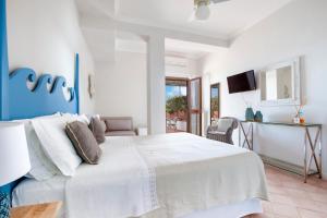 - une chambre avec un grand lit blanc et une télévision dans l'établissement Il Cefalo Hotel & Restaurant, à Castellabate