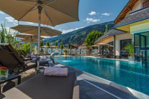 una piscina in un hotel con sedie e ombrelloni di Hotel Post a Kaltenbach