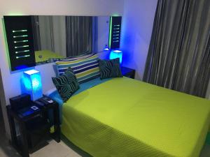 a bedroom with a green bed with blue lights at Alegria Hostal in Santiago de los Caballeros