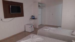 a small room with two beds and a television at Pousada Rio Grande in Santo Amaro