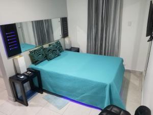 a bedroom with a blue bed with a mirror at Alegria Hostal in Santiago de los Caballeros