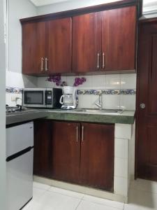 a kitchen with wooden cabinets and a microwave at Alegria Hostal in Santiago de los Caballeros