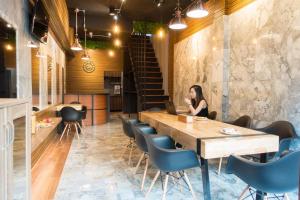 a woman sitting at a table in a restaurant with a laptop at Comfy Bed Hostel in Bangkok