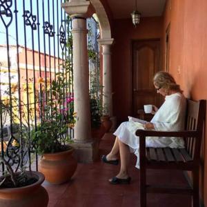 a woman sitting on a bench reading a book at Hostal de Las Américas in Oaxaca City