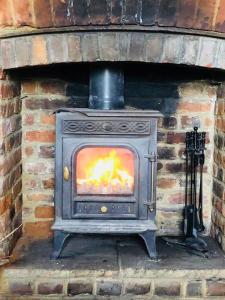 a stove in a brick oven with a fire in it at Wisteria Cottage in Gravesend