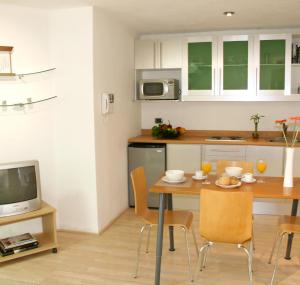 a kitchen with a table with chairs and a television at Hotel Piedraluna in Guatemala