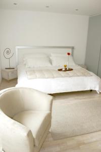 a white bedroom with a white bed and a chair at Hotel Piedraluna in Guatemala