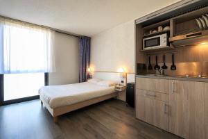 um quarto de hotel com uma cama e uma cozinha em Hôtel des Thermes Les Dômes em Vichy