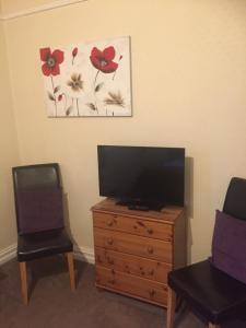 a living room with a tv on a dresser and two chairs at Westbury House in Windermere