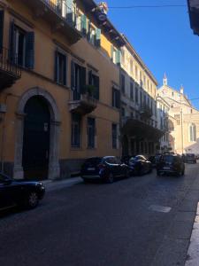 Une rangée de voitures garées dans une rue à côté des bâtiments dans l'établissement Duomo apartment, à Vérone